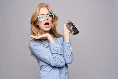 blonde in glasses does not know what to do with the camera in her hand.の写真素材