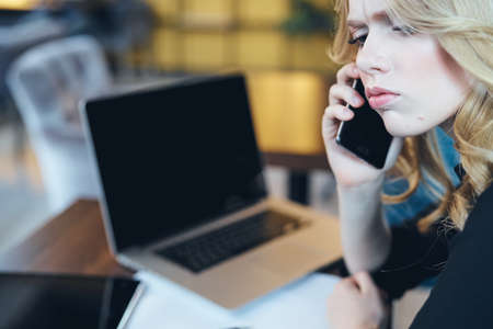 girl angrily communicates on a phone in front of a laptop in the office.の写真素材