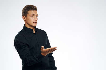 a man in a black shirt with an outstretched hand on a light background.の写真素材