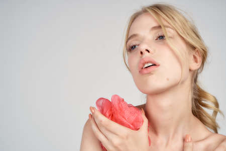woman holds a loofah on a light background, plenty of space for copying.の写真素材