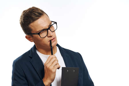 a man in glasses gnaws a pencil holds a notepad and thinks.の写真素材