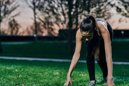 girl in a pose ready to run on a green background.の写真素材