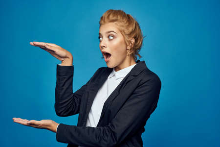 girl in a suit on a blue background shows her hands something big.の写真素材
