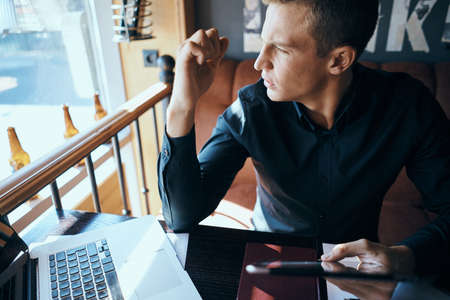 a man holds a tablet in his hand and looks out the window.