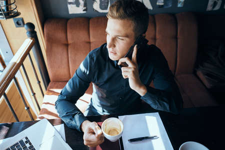 man in a cafe talking on the phone and looking out the window.の写真素材