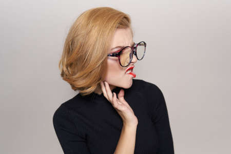 blonde in glasses is unhappy on a light blue background.の写真素材