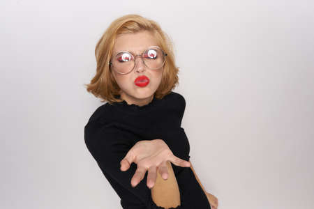 blonde in glasses blowing and showing direction.の写真素材