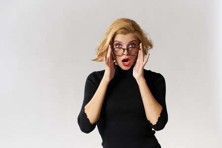 blonde holding her glasses and wondering.の写真素材