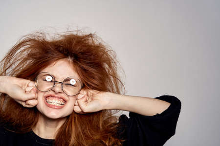 shaggy girl in glasses is very happy with her hands near the face.の写真素材