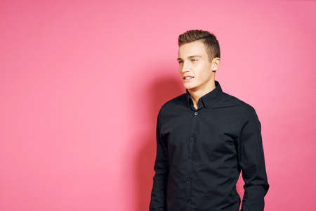 man in a black shirt smiles on a pink background.の写真素材