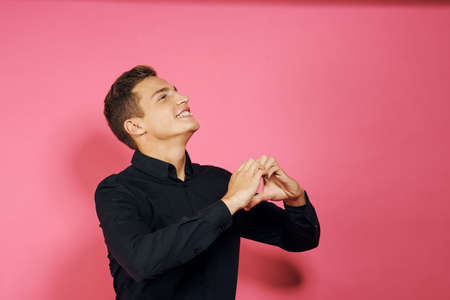a man in a black shirt shows his hands the heart in the other direction.の写真素材