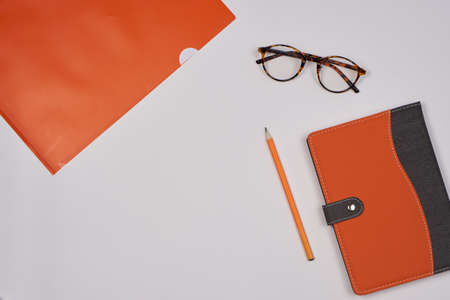 white background, glasses, orange pencil, folder, notepad.の写真素材