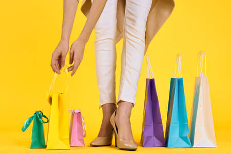 legs of a girl, hands reaching for a package, yellow background.の写真素材
