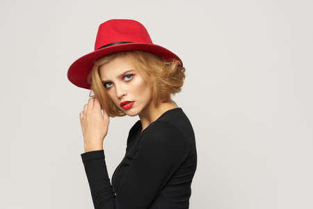beautiful woman in a red hat and a black sweater on a light background.の写真素材