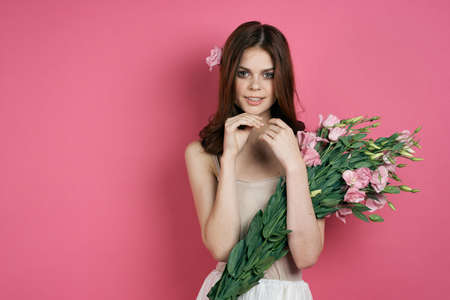 girl with a bouquet of flowers on a pink background.の写真素材