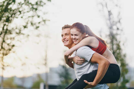 A guy is holding the girl on his back. sport on the background of nature.の写真素材