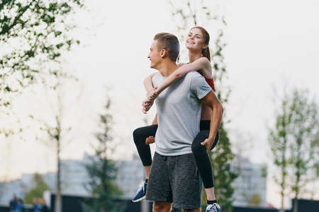 the guy is holding the girl in his back on the background of the trees.の写真素材