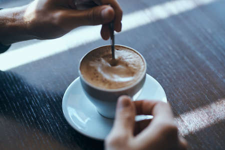 A hand stirring a cup of coffeeの写真素材