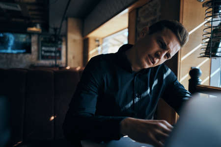 a man peers at something on a laptop.の写真素材