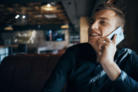 a man in a black shirt speaks happily on the phone.の写真素材