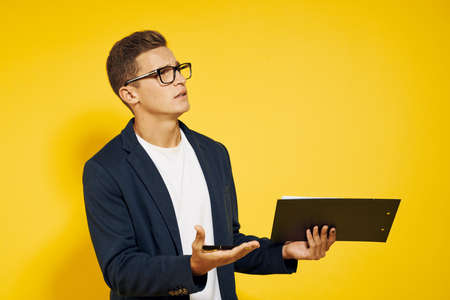 business man with glasses and a folder in his hands looks aside.の写真素材