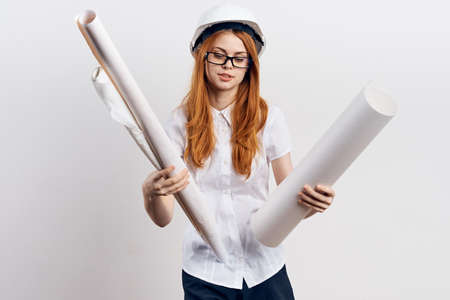 Female engineer wearing helmet and holding drawings in both handsの写真素材