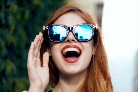 portrait of a bright girl with gleams in glasses on a background of leaves.の写真素材