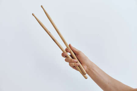 hand with drumsticks on a light background.の写真素材