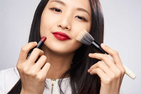 Asian woman applies make-up on white background.の写真素材