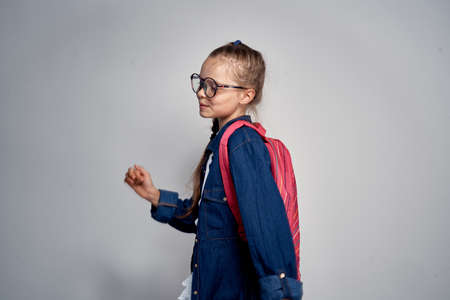 schoolgirl with a backpack on a gray background.の写真素材