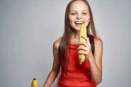 happy young girl in red dress with bananas.の写真素材