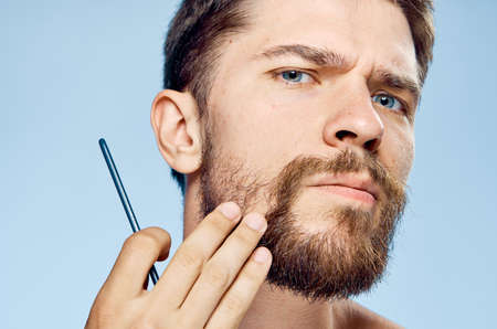 the man pensively examines his beard and is about to shave.の写真素材