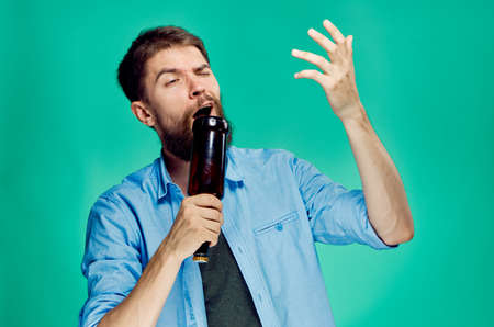 man on a green background trying to use a bottle as a microphone.の写真素材