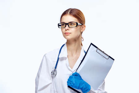 female doctor holding a folder in her hand, glasses, stethoscope, light background.の写真素材