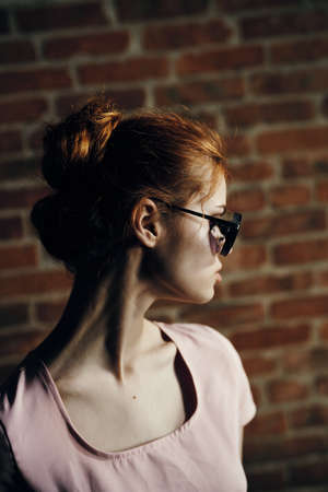 portrait of a redhead girl on a brick wall background.