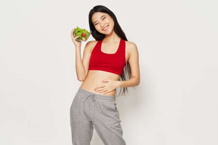 Sportswear beautiful woman in a red T-shirt diet vegetables in a plate modelの写真素材