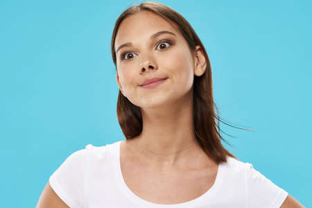 Blue background beautiful girl wide open eyes white tank topの写真素材