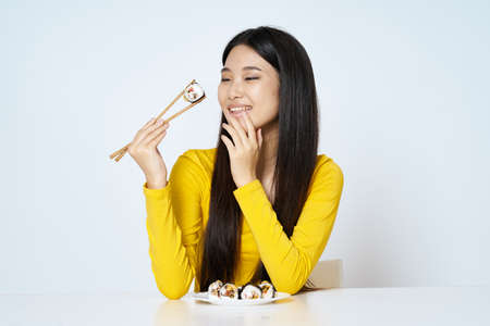 Woman in yellow sweater diet sushi rolls traditionの写真素材