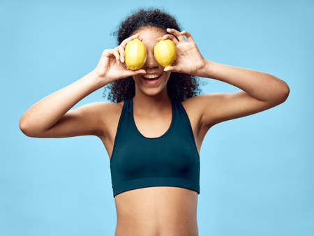 Beautiful woman with two lemons near her face laughing