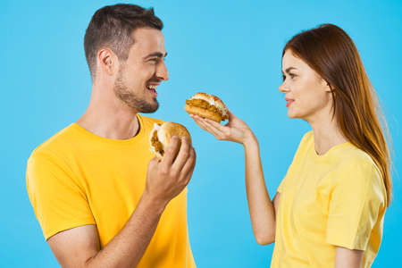 Cheerful young couple in yellow t-shirts hamburger fast foodの写真素材