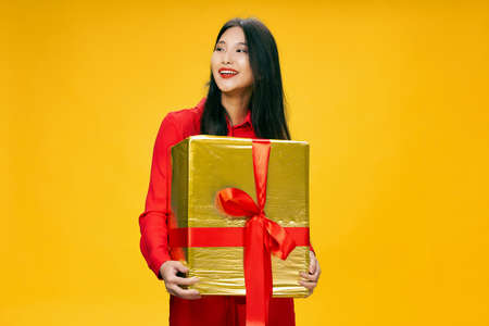 Happy woman in a red coat with a gift box laughsの写真素材