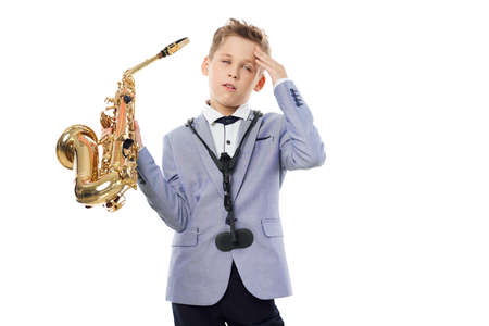 Baby girl in a classic suit with a saxophone in handの写真素材