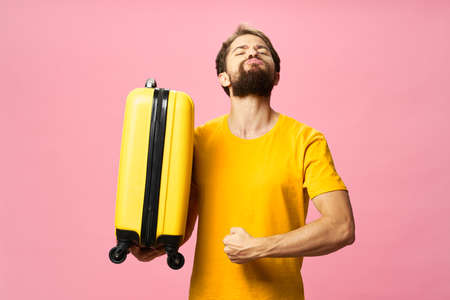 Confident man go on a trip with a yellow suitcaseの写真素材