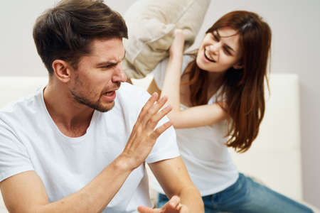 Happy man and woman fight pillows on the bed
