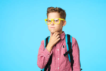Puzzled by schoolchildren with a backpack on their back and yellow glassesの写真素材