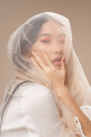 Woman with transparent cloth touches her face with her hand Asian