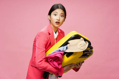 Surprised traveler holds in her hands a suitcase with clothes