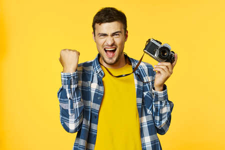 man in a yellow T-shirt with a camera in his hand is a joy emotion modelの写真素材
