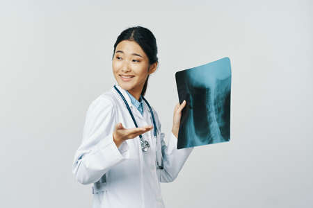 Professional woman doctor in a medical coat holds an x-ray in his handの写真素材