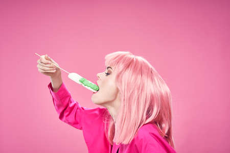 Beautiful woman in a pink shirt eats a cake on an isolated background discoの写真素材